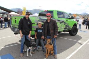 People and their dogs in front of a Green Pick Up Truck